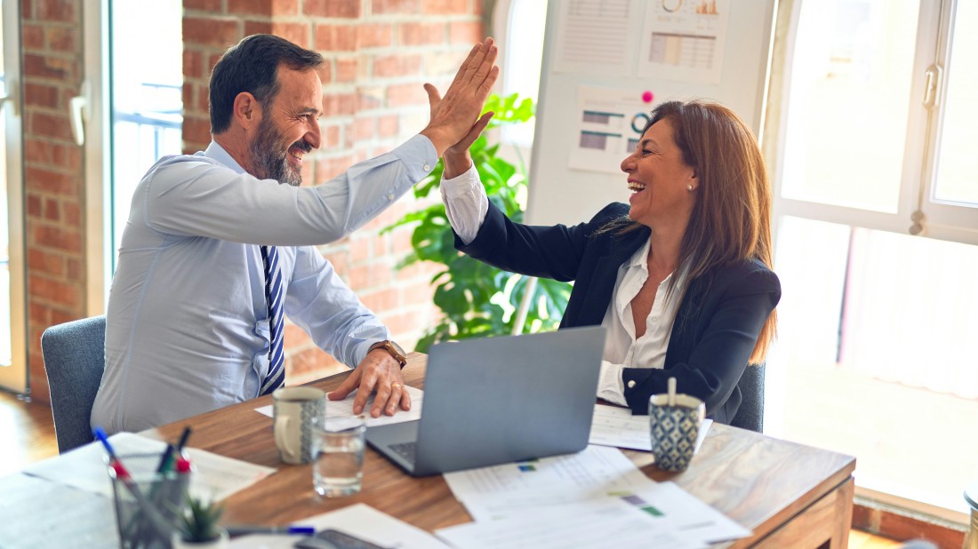 Ein Mann und eine Frau geben sich bei der Arbeit ein Highfive.